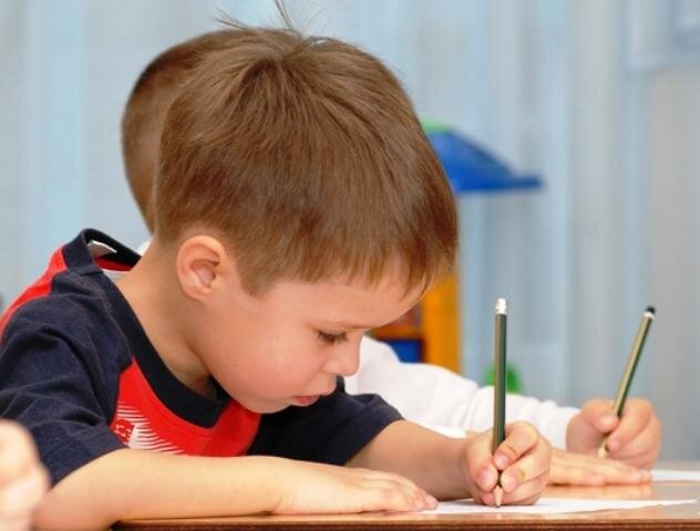 Ребенок левша пишет в тетрадь